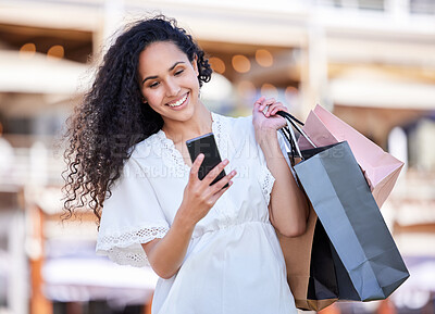 Buy stock photo Shot of a young woman using a smartphone while shopping against an urban background