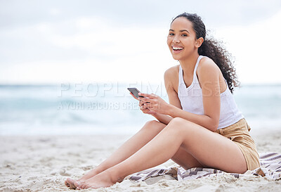 Buy stock photo Shot of a young woman using a phone at the beach