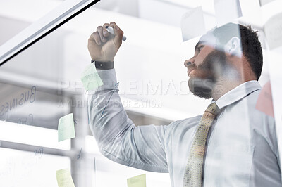 Buy stock photo Low angle shot of a young businessman writing notes on a glass wall in an office
