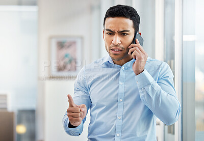Buy stock photo Shot of a young businessman looking angry while making a phone call using his smartphone