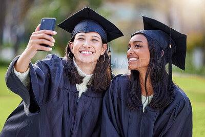 Buy stock photo Cropped shot of two attractive young female students taking selfies while celebrating on graduation day
