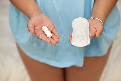 Buy stock photo Shot of an unrecognisable woman holding a tampon and sanitary towel