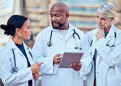 Buy stock photo Shot of a group of doctors using a digital tablet in the city