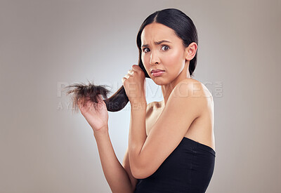 Buy stock photo Shot of an attractive young woman holding her hair and looking worried while posing in the studio