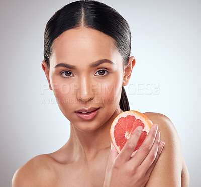 Buy stock photo Studio portrait of a beautiful young woman posing with grapefruit against a grey background