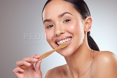 Buy stock photo Studio portrait of a beautiful young woman brushing her teeth against a grey background