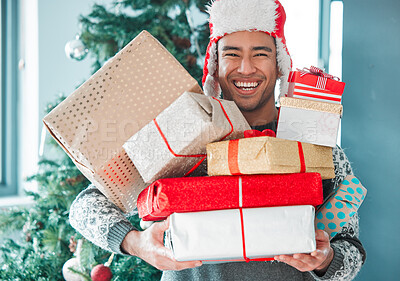 Buy stock photo Shot of a young man holding his Christmas gifts at home