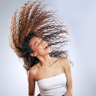 Buy stock photo Cropped shot of an attractive young woman whipping her hair in studio against a grey background