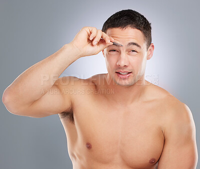 Buy stock photo Shot of a handsome young man tweezing his eyebrows