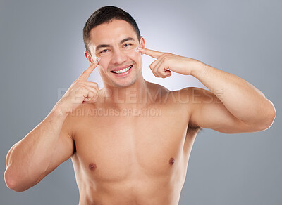 Buy stock photo Shot of a handsome young man applying lotion to his face