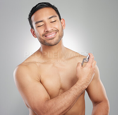 Buy stock photo Studio shot of a handsome young man applying perfume against a grey background
