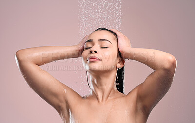 Buy stock photo Shot of a young woman rinsing her hair against a studio background