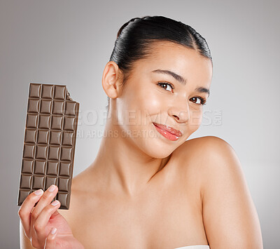 Buy stock photo Studio shot of an attractive young woman eating a slab of chocolate against a grey background