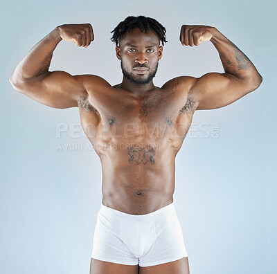Buy stock photo Studio shot of a handsome young man flexing his muscles