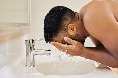 Buy stock photo Shot of an unrecognisable man washing his face in his bathroom at home