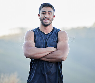 Buy stock photo Shot of a handsome young man standing alone outside with his arms crossed after running