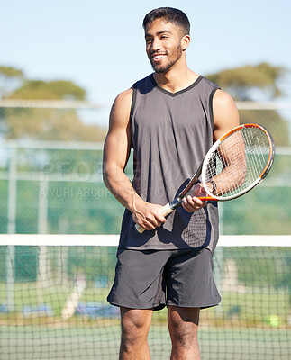 Buy stock photo Shot of a handsome young man standing alone and playing tennis outside