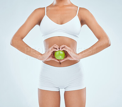 Buy stock photo Cropped shot of an unrecognisable woman standing alone in the studio and posing with an apple