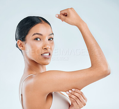 Buy stock photo Shot of an attractive young woman standing alone in the studio and pulling at fat around her arm