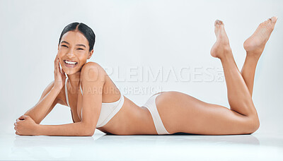 Buy stock photo Full length shot of a young woman lying down in the studio and posing in her underwear
