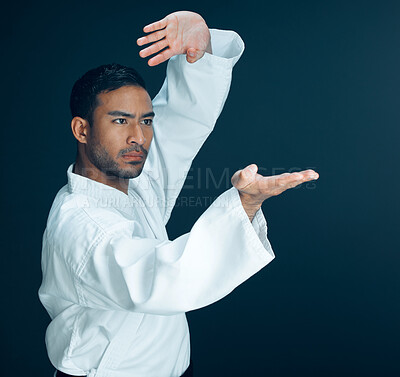 Buy stock photo Cropped shot of a handsome young male martial artist practicing karate in studio against a dark background