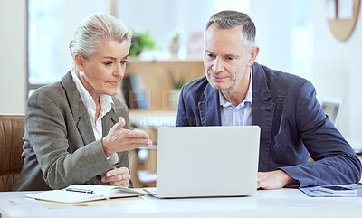 Buy stock photo Shot of two businesspeople using a laptop together in an office at work