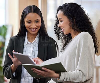 Buy stock photo Shot of two businesswomen working together while using a digital tablet