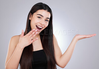 Buy stock photo Studio shot of an attractive young woman looking surprised while pointing to copyspace against a grey background