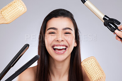 Buy stock photo Studio portrait of an attractive young woman surrounded by haircare products against a grey background
