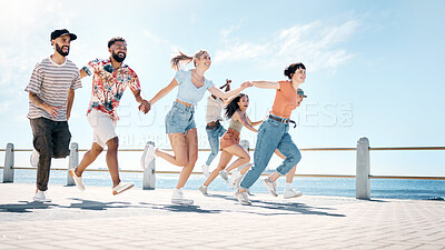 Buy stock photo Full length shot of a diverse group of friends bonding and holding hands while running outdoors together