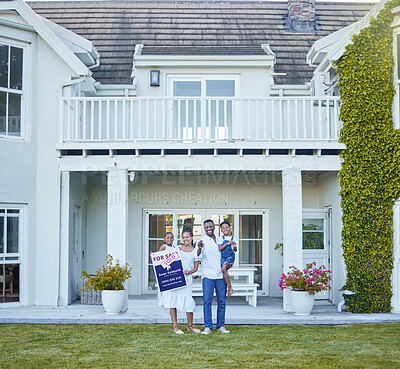 Buy stock photo Shot of a young family posing in front of a house with a sold sign