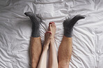 Closeup of the legs of a couple lying in bed affectionately cuddling