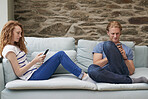 A young couple using smartphones while spending time together at home