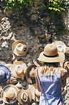 Woman shopping for hats in Italy on summer vacation. Rear view of woman exploring town in Italy