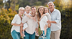 Portrait of multi-generation family standing together. Extended caucasian family smiling while spending time together at the park on a sunny day. Family with two children, parents and grandparents 