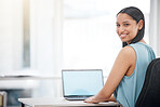Portrait of a Happy young mixed race businesswoman smiling while enjoying working on a laptop sitting in a chair in an office at work. One hispanic female boss sending an email using a laptop at a desk at work