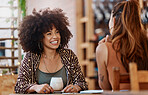 Smiling young african american woman with curly afro sitting and bonding with friend in a cafe and drinking a matcha tea. Mixed race woman laughing with a friend in a coffee shop. Talking over coffee
