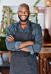 Confident young african american entrepreneur standing with his arms crossed in a cafe. One proud coffeeshop owner managing small business startup. Barista and waiter ready to serve customers in store