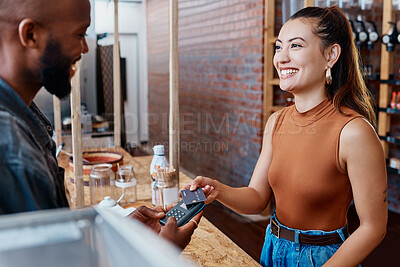 Buy stock photo Happy hispanic customer paying for a meal in a restaurant using a nfc machine and credit card. Smiling young woman making a purchase in a store with her debit card and a pos machine. Woman paying bill