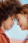 Shot of two young mixed race female friends embrace and smiling outside on a sunny day. A Beautiful gay hispanic woman with a cool afro hair style being affectionate with her asian partner 