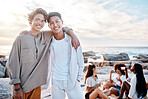 Portrait of two attractive young men standing together on the beach. Asian male and his best friend embracing one another on a day out with friends