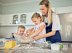 Smiling caucasian mother with two adorable daughters baking at home. Mom and kids mixing batter or ingredients in bowl for pancakes or dough for cookies. Mom and little helpers cooking in kitchen 