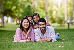 Portrait of happy asian family lying on grass in a park. Adorable little girls spending time with mom and dad on a weekend outside. Smiling couple lying on lawn with their daughters on their back