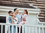 Happy young mixed race family with two children standing outside on their balcony at home. Loving couple with their daughter and son wearing pyjamas and enjoying their new house