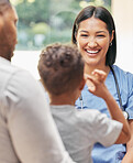 Caring female nurse working with a family. Friendly nurse talking to little boy during hospital visit with his father