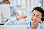 Excited asian businessman celebrating a success cheering and punching the air with his fists as he sits at a desk. One call centre agent with headset cheering after making a sale or reaching target