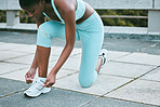 One fit young african american woman tying her shoelaces while exercising outside. Black athlete fastening sneaker footwear for a comfortable fit and to prevent tripping during a training workout in the city
