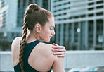 One young caucasian woman holding her sore shoulder while exercising outdoors. Female athlete suffering with painful arm injury from fractured joint and inflamed muscles during workout. Struggling with stiff body cramps causing discomfort and strain