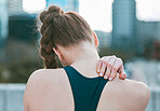 Closeup of one caucasian woman from behind holding neck shoulder while exercising outdoors. Female athlete suffering with painful injury from fractured joint and inflamed muscles during workout. Struggling with stiff body cramps causing discomfort