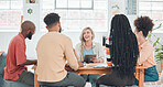 Group of diverse businesspeople having a meeting in a modern office at work. Young happy caucasian businesswoman smiling while working on a digital tablet in a boardroom with colleagues. Creative businesspeople planning together